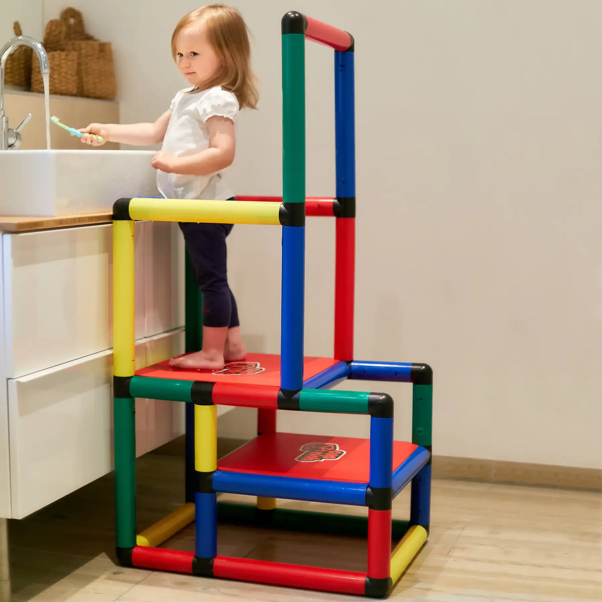 Child washing hands from a two-step QUADRO learning tower at a sink