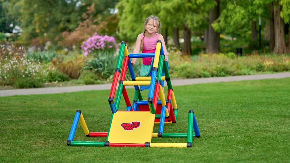 Child climbing a colourful QUADRO parkour frame with ramp on a lawn