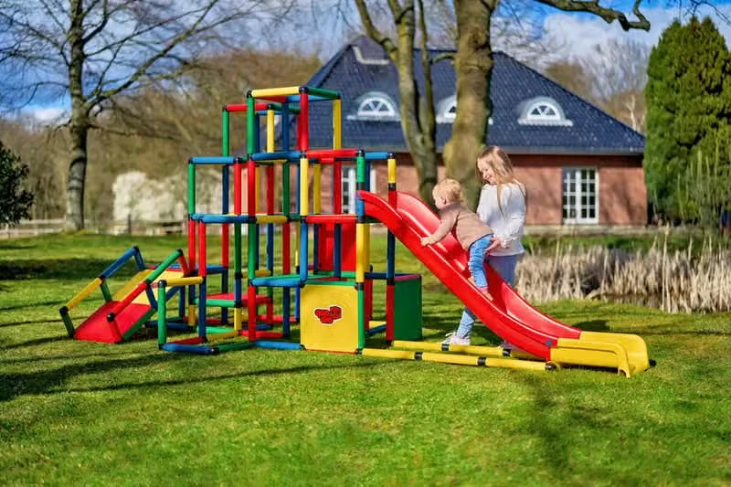 Children playing on a large outdoor QUADRO climbing tower with modular red slide