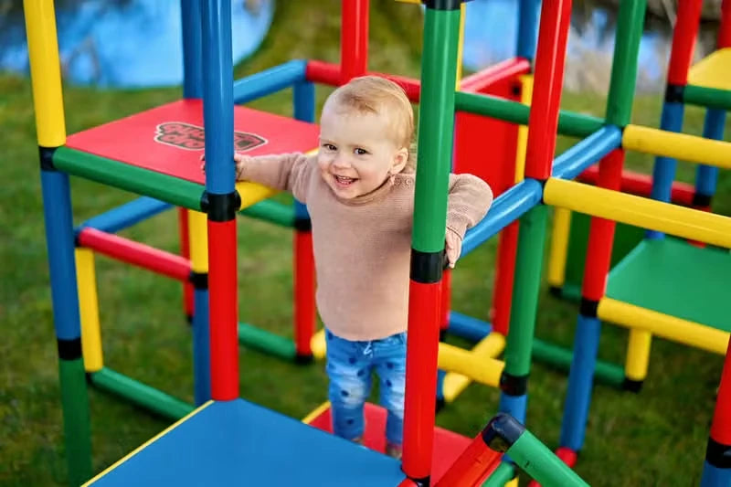 Smiling toddler walking through the bars of a large QUADRO climbing frame