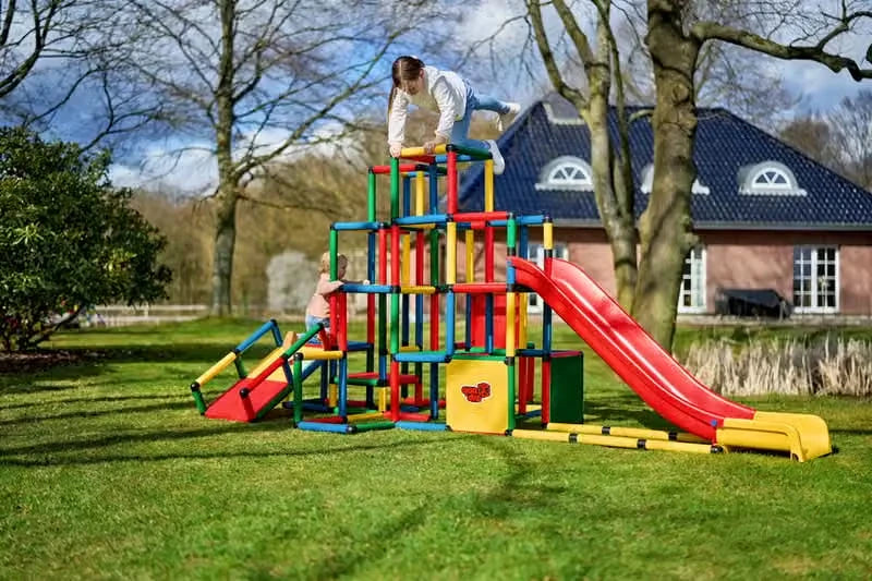 Child climbing on top of a large QUADRO tower with modular red slide