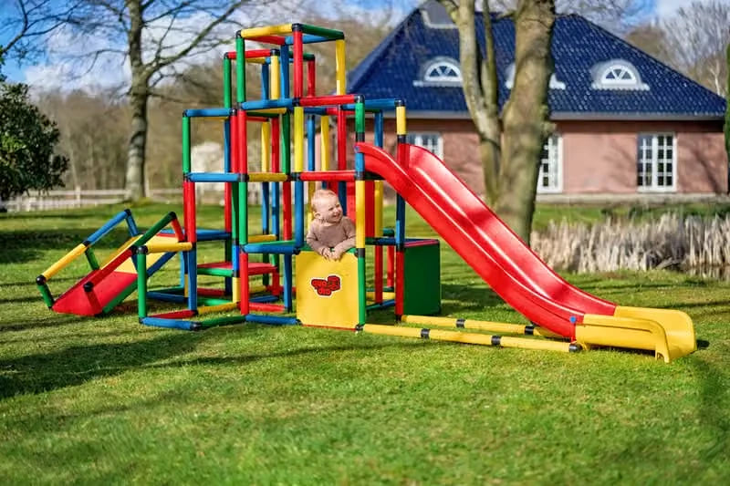Child seated at the base of a long modular red slide on a QUADRO tower