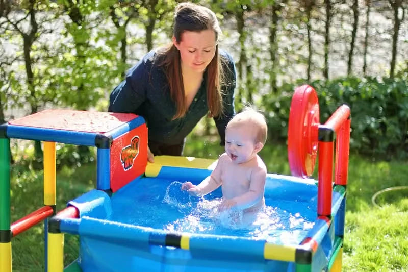 Baby splashing in a small blue QUADRO pool while an adult supervises