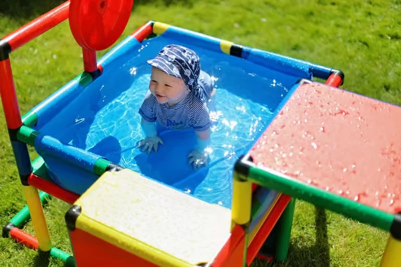 Baby sitting in a compact blue QUADRO pool with surrounding platforms