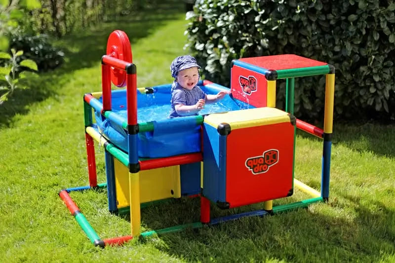 Baby seated in a compact QUADRO pool with play panels and red wheel