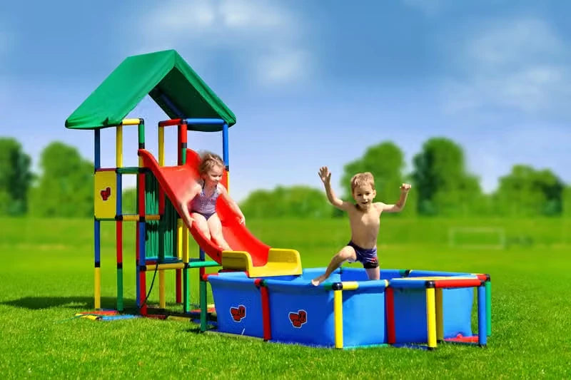 Two children using a modular red slide beside a large QUADRO pool